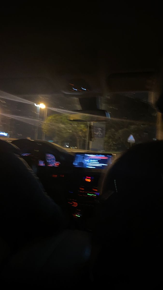 the interior of a car at night with lights on and people sitting in the passenger seat