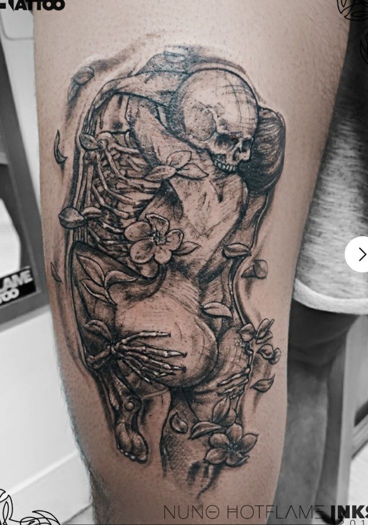 a black and white tattoo on the leg of a person with a skull in it