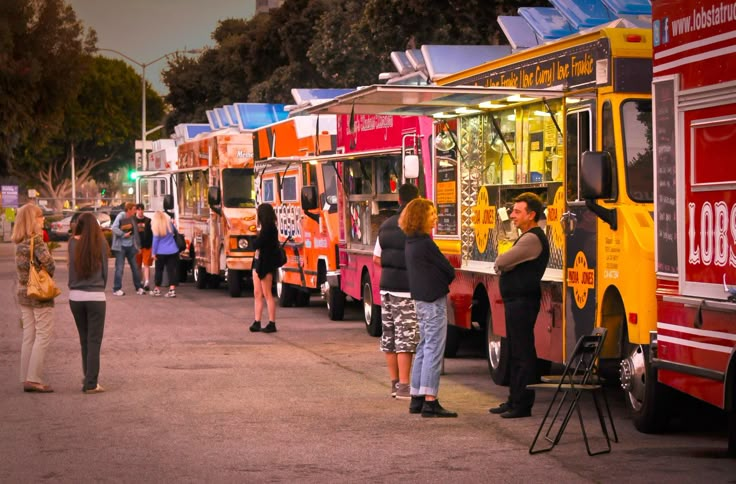 people are lined up to buy food from trucks