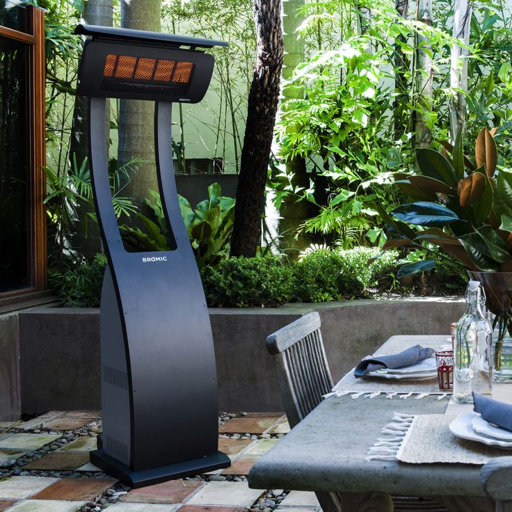 an outdoor dining area with a table and chairs in the foreground, surrounded by greenery