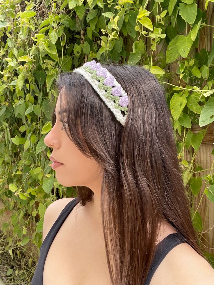 a woman with long hair wearing a headband made out of crocheted yarn