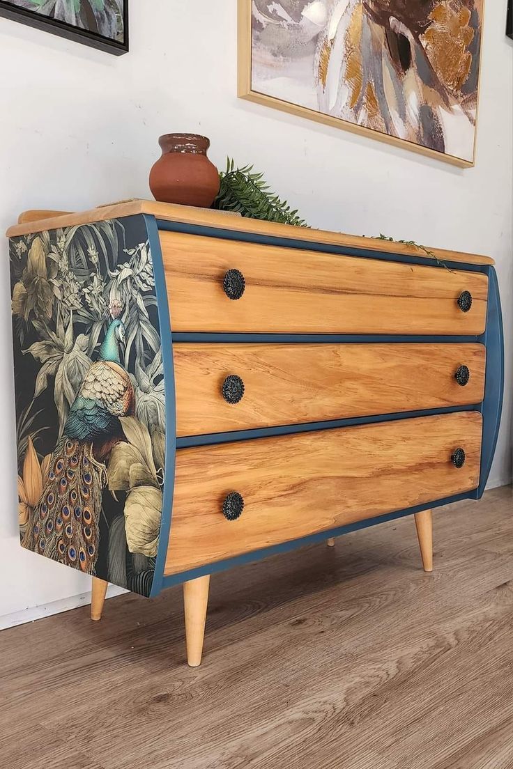 a wooden dresser sitting on top of a hard wood floor next to a wall with pictures above it