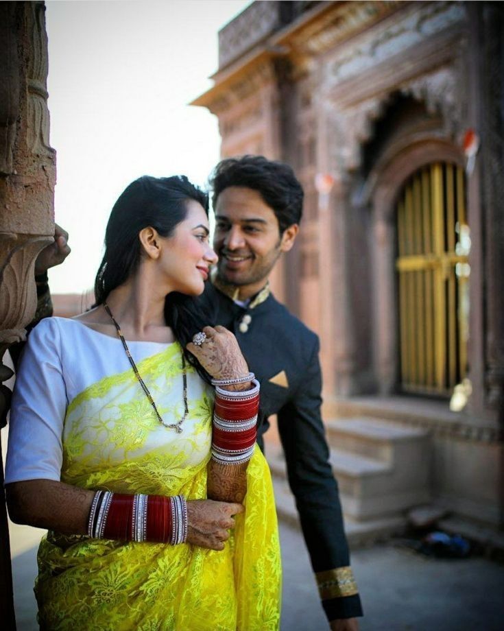 a man and woman standing next to each other in front of an old building,