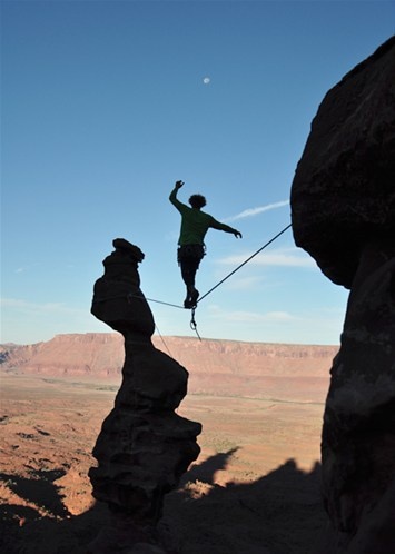 a man standing on top of a cliff while holding onto a rope