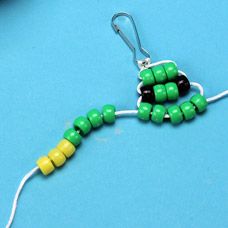 a pair of green and yellow beaded earrings on a blue surface with beads attached to them