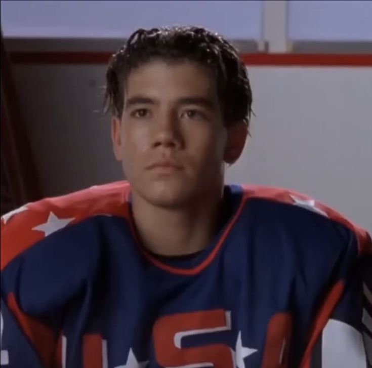 the young man is wearing an american football jersey and looking at the camera while sitting down