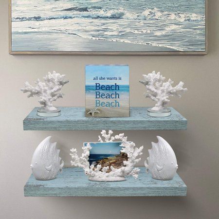 two white shelves with seashells on them in front of a painting and an ocean scene