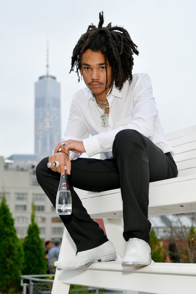 a man with dreadlocks sitting on a bench next to a bottle of water