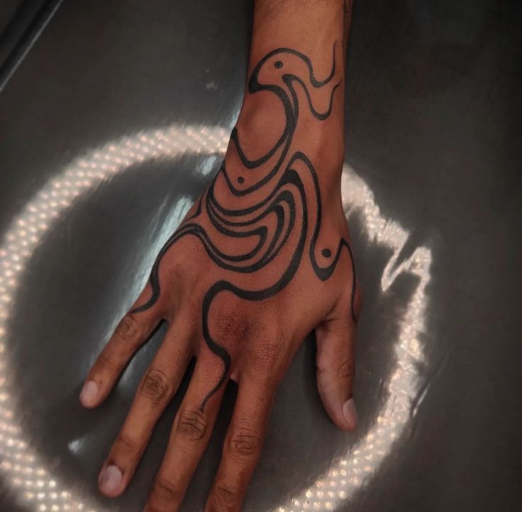 a person's hand with a black and white tattoo design on the middle of it