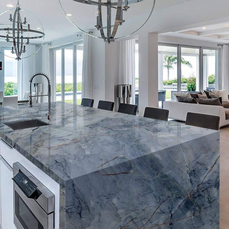 a kitchen with marble counter tops and an island in front of a living room area