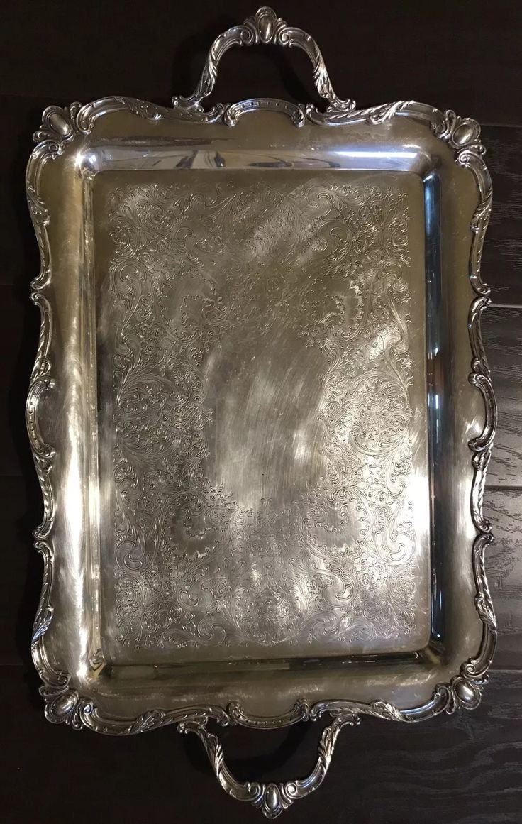 an ornate silver tray with handles on a wooden table