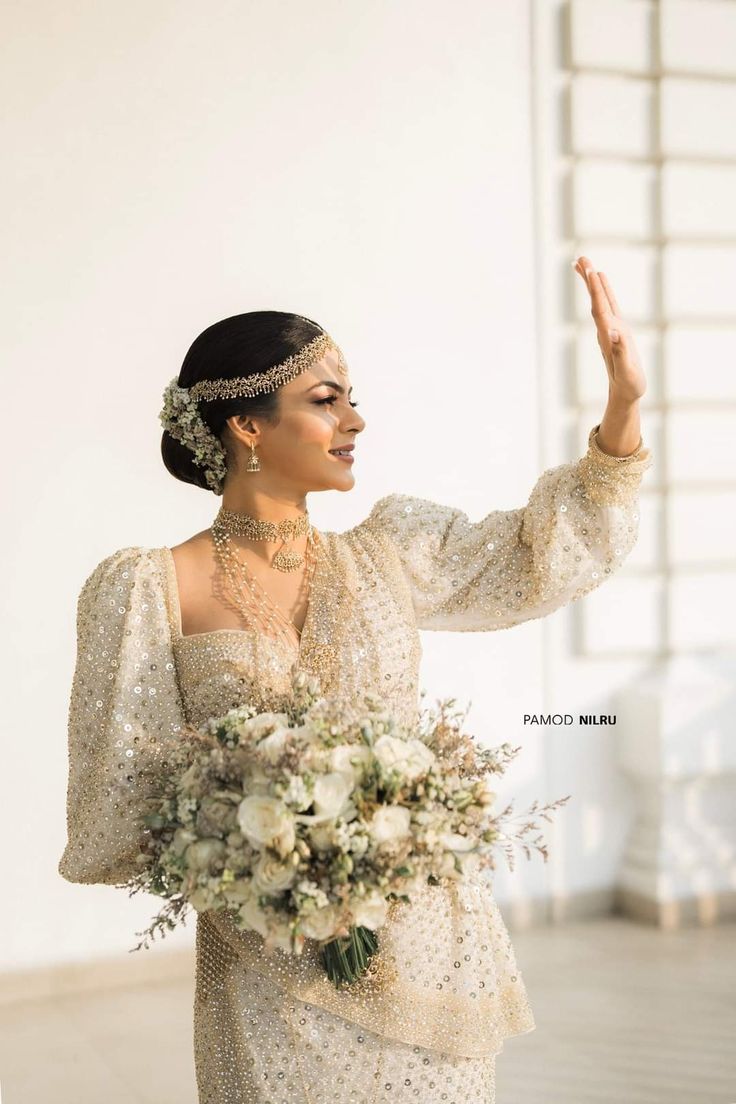 a woman in a white dress holding a bouquet and pointing to the side with her right hand