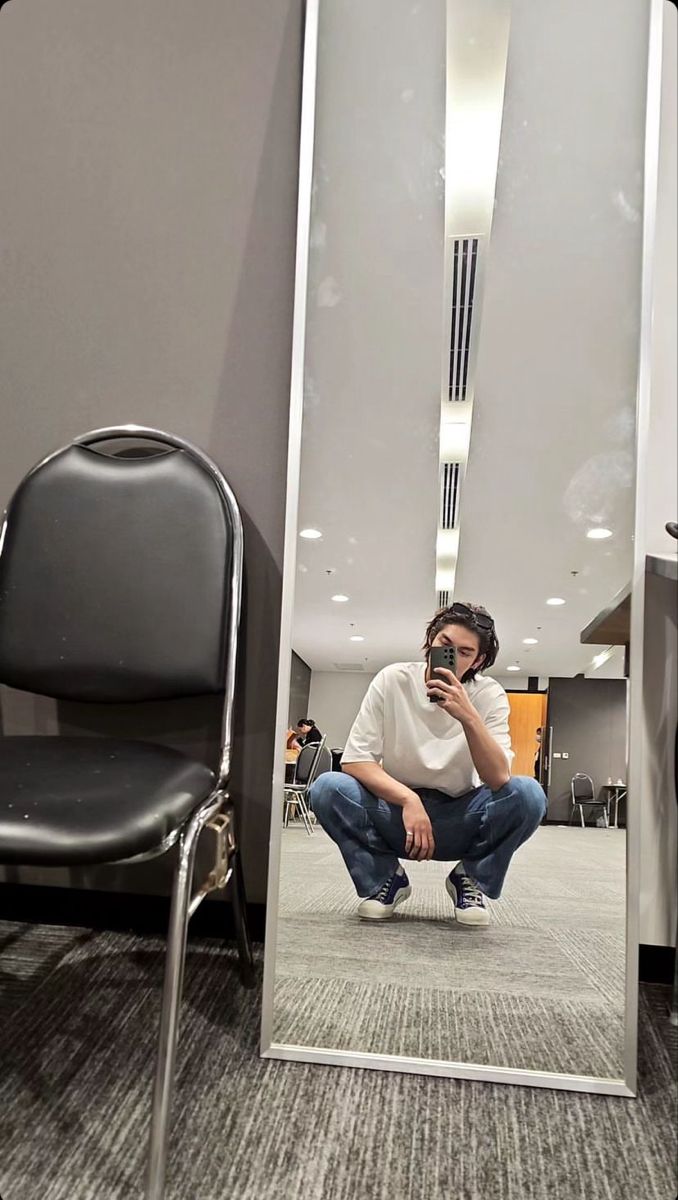 a man sitting in front of a mirror taking a selfie with his cell phone