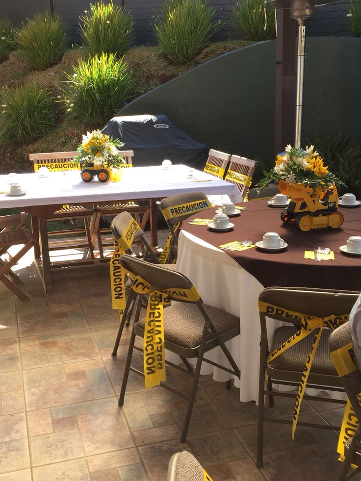 a table set up with yellow and white ribbons around it for an outdoor party or gathering