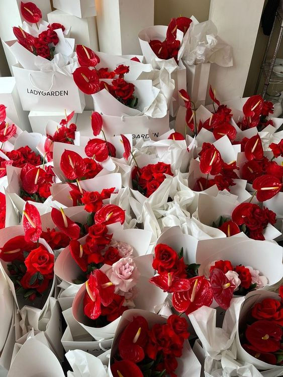 many red roses are in white paper bags