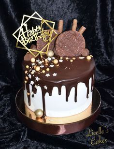 a birthday cake with chocolate icing and cookies on top, decorated with gold stars