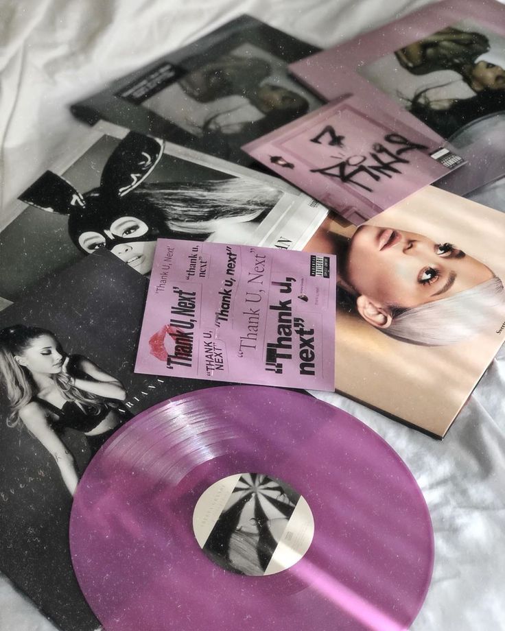 purple vinyl records are laying on a white sheet with black and white photos in the background