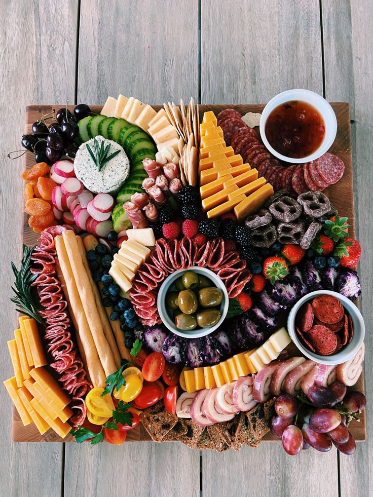 a platter filled with meats, cheeses, and other foods on top of a wooden table