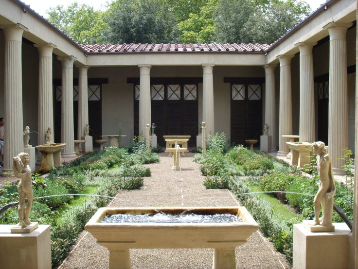 an outdoor courtyard with statues and water feature in the center, surrounded by greenery