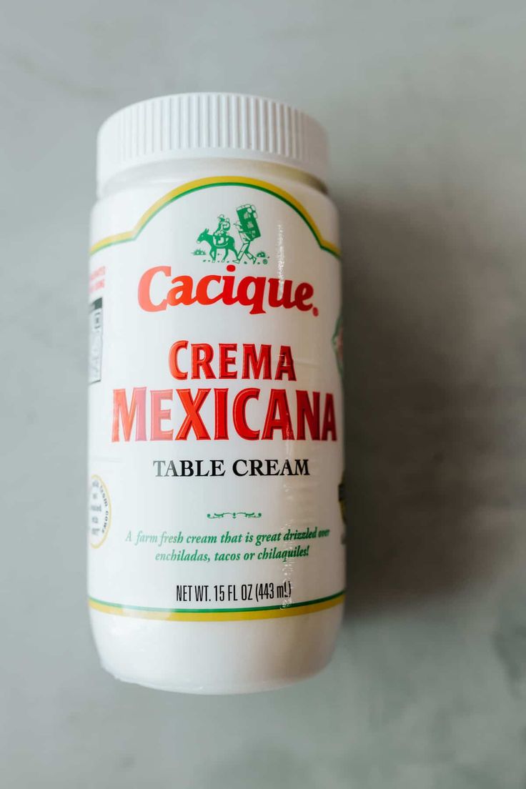 a bottle of cacique cream sitting on top of a white countertop next to a wall