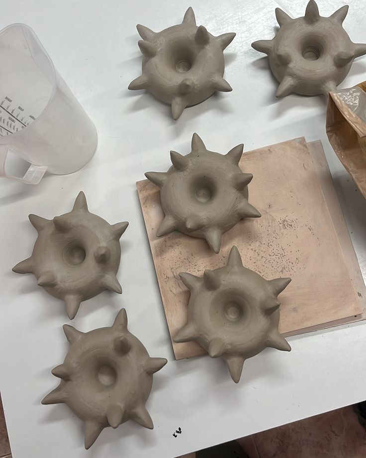 several clay spiky objects sitting on a table next to a bottle and paper