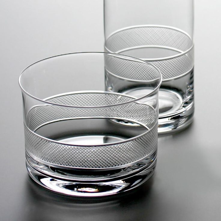 two glasses sitting on top of a table next to each other with water in them