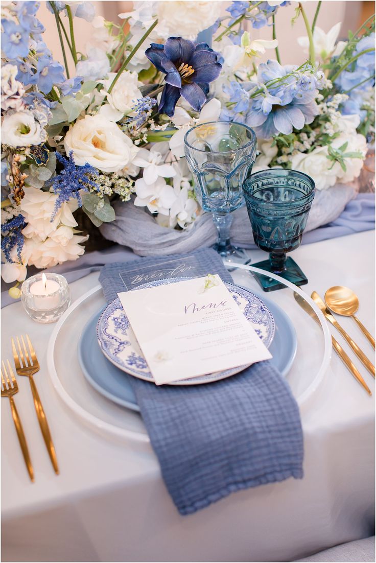 a blue and white table setting with flowers