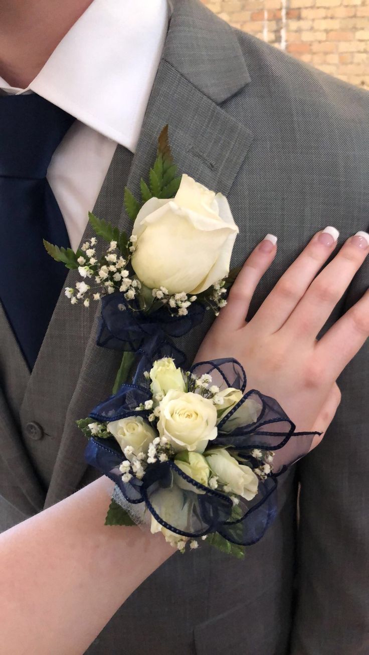 a man and woman wearing boutonnieres with flowers on their fingers, both holding each other's hands