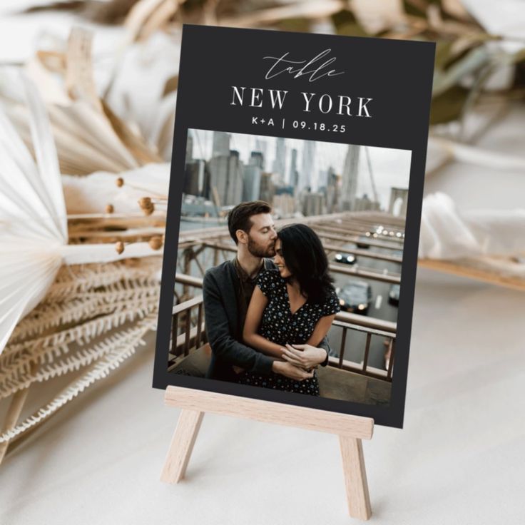 an easer holds a photo of a couple in new york, with the city skyline behind them