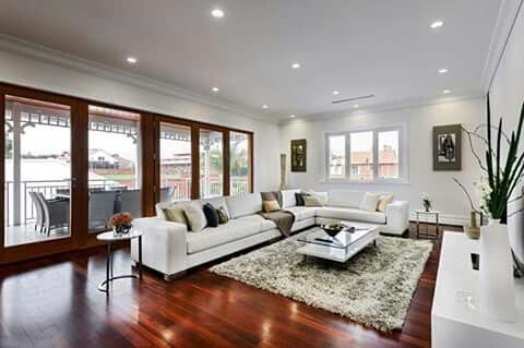 a living room filled with furniture and lots of windows on top of a hard wood floor