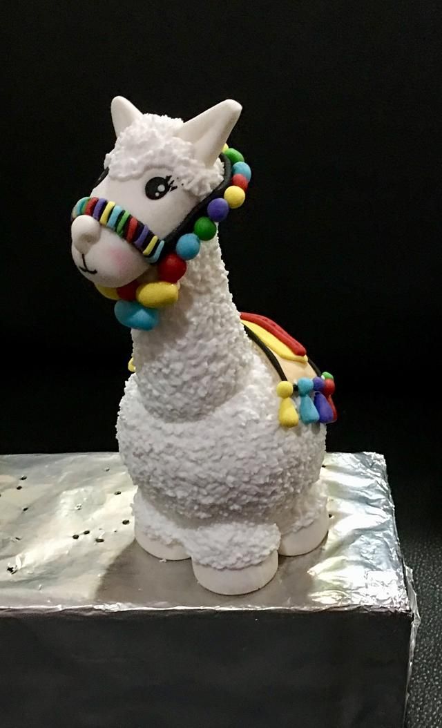 a white llama figurine with beads around its neck on a silver surface