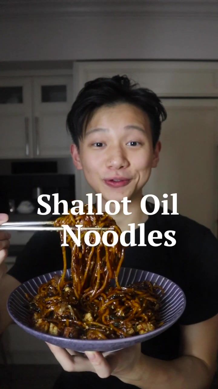 a man holding a plate with food on it and the words shallot oil noodles