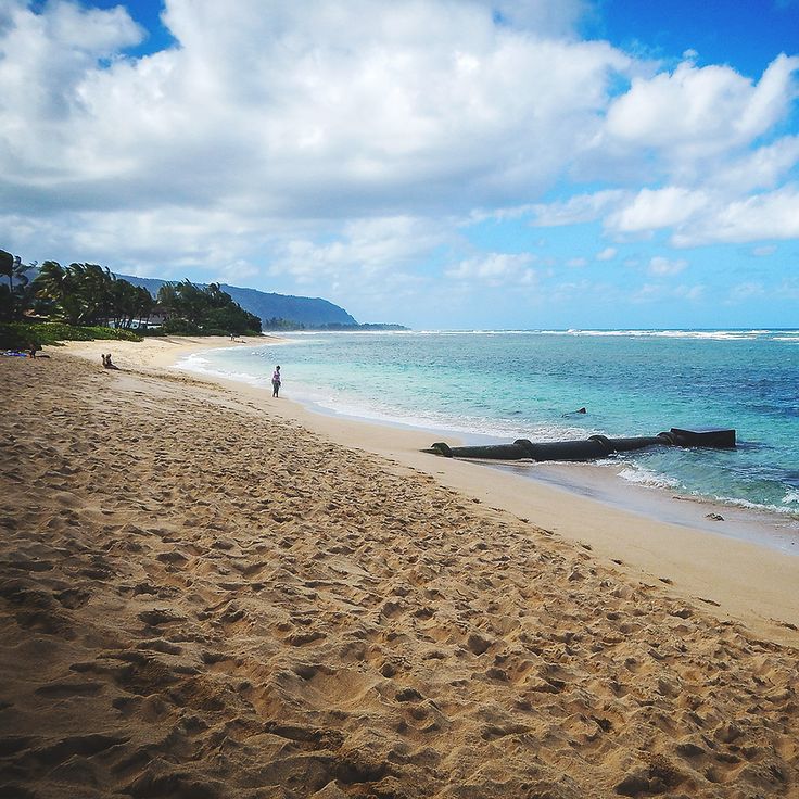 a beach with people walking on it next to the ocean