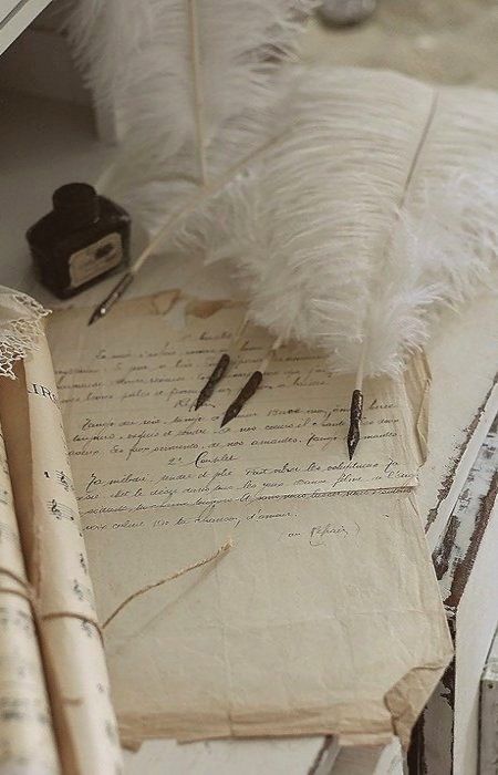 an old book with writing on it sitting next to a feather pen and inkwell