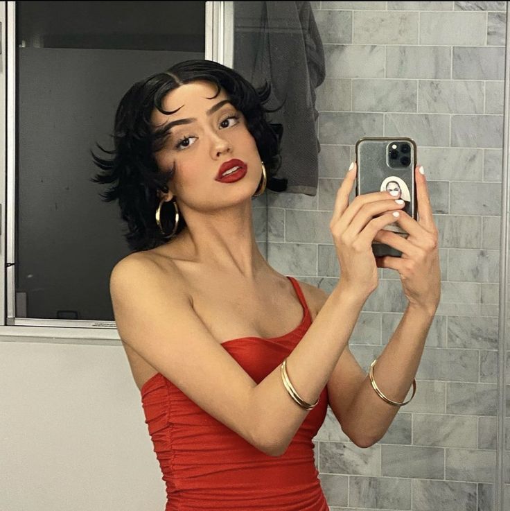 a woman in a red dress taking a selfie with her cell phone while standing in front of a mirror