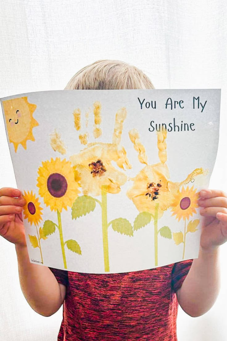 a child holding up a card with sunflowers on it that says you are my sunshine