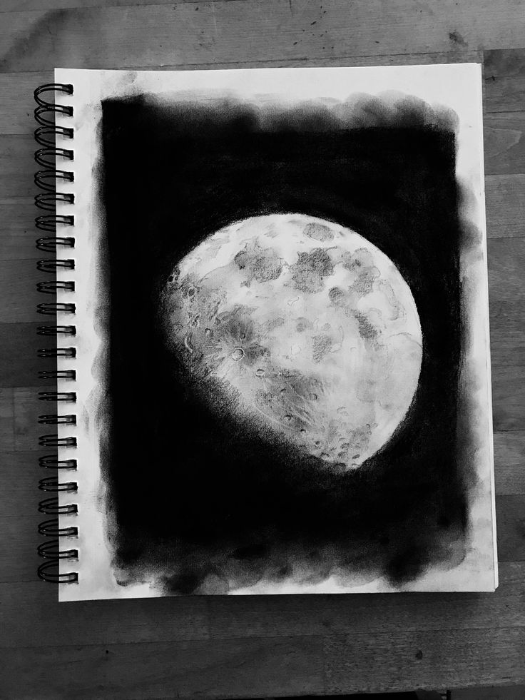 a black and white drawing of the moon on a piece of paper next to a pen