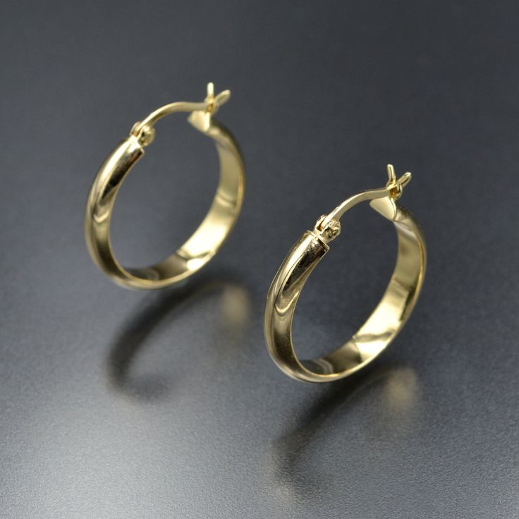 The unsung hero of the typical jewelry collection: wear-every-day golden hoop earrings. The best ones always strike the note of "platonic ideal" - not too big or too small, lightweight and easy for daily wear. These have a half-round profile with a domed outer edge and are fashioned from 14 karat yellow gold. They feature a slight chunkiness to them that makes them really special. The earrings secure by a slightly curved, hinged ear-wire that fastens in a U-shaped catch. More details: 21.6mm fro Minimalist Hoop Earrings With Shiny Finish For Formal Occasions, Minimalist 14k Gold Hoop Earrings With Shiny Finish, Fine Jewelry Polished Hoop Earrings For Everyday, Polished Fine Jewelry Hoop Earrings For Everyday, Classic Small Hoop Rings For Formal Occasions, Everyday Fine Jewelry Hoop Earrings With Polished Finish, Everyday Polished Hoop Earrings In Fine Jewelry Style, Minimalist Yellow Gold Hoop Earrings With Shiny Finish, Minimalist 14k Gold Earrings With Shiny Finish