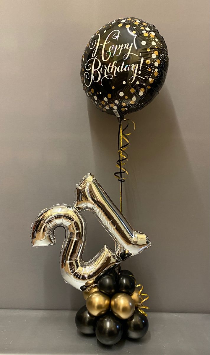 a black and gold 50th birthday balloon sitting on top of a table next to some balloons