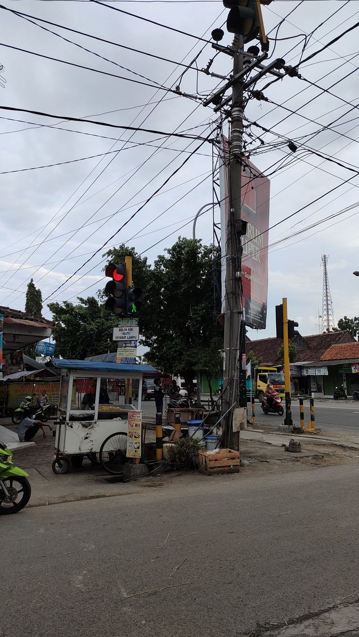 an intersection with traffic lights and cars on the road, in front of power lines