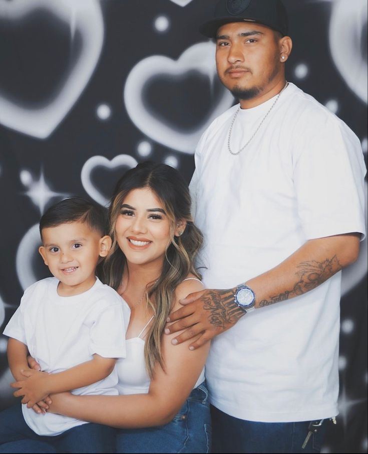 a man, woman and child posing for a photo in front of a wall with hearts