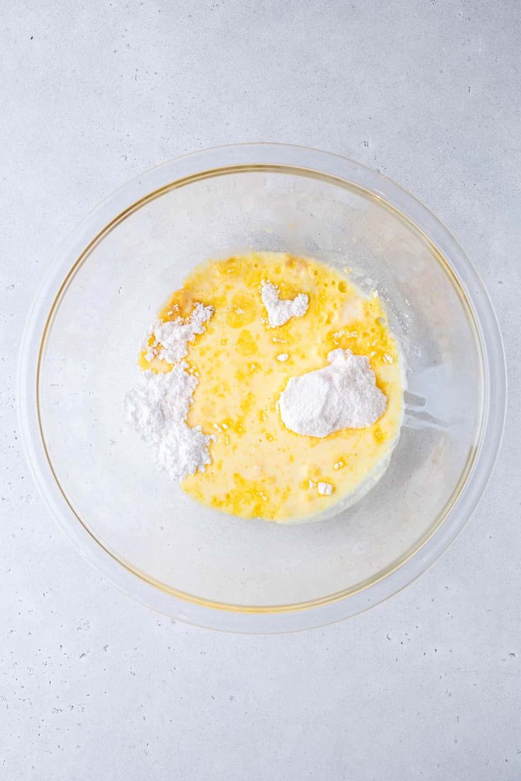 a bowl filled with eggs and flour on top of a table