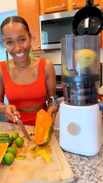 a woman is cutting up some fruit on the kitchen counter with a juicer and blender in front of her