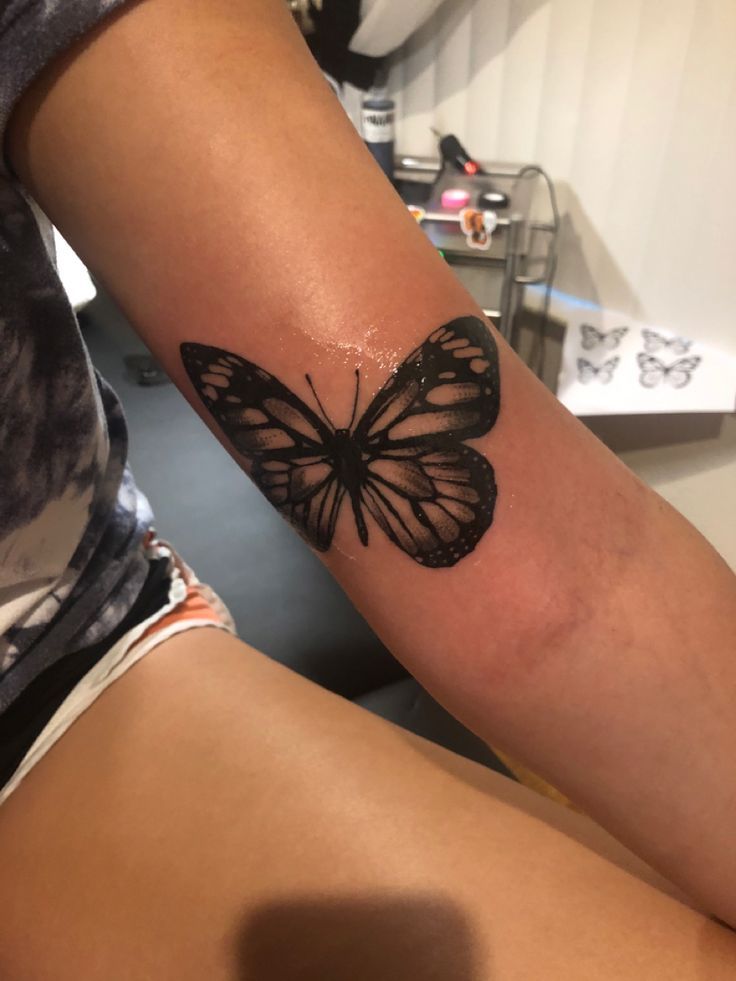 a woman's arm with a butterfly tattoo on the left side of her body