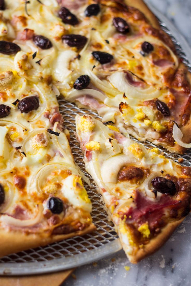 a pizza sitting on top of a metal pan covered in cheese and black olives