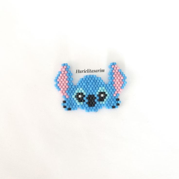 a blue beaded stitched brooch sitting on top of a white surface