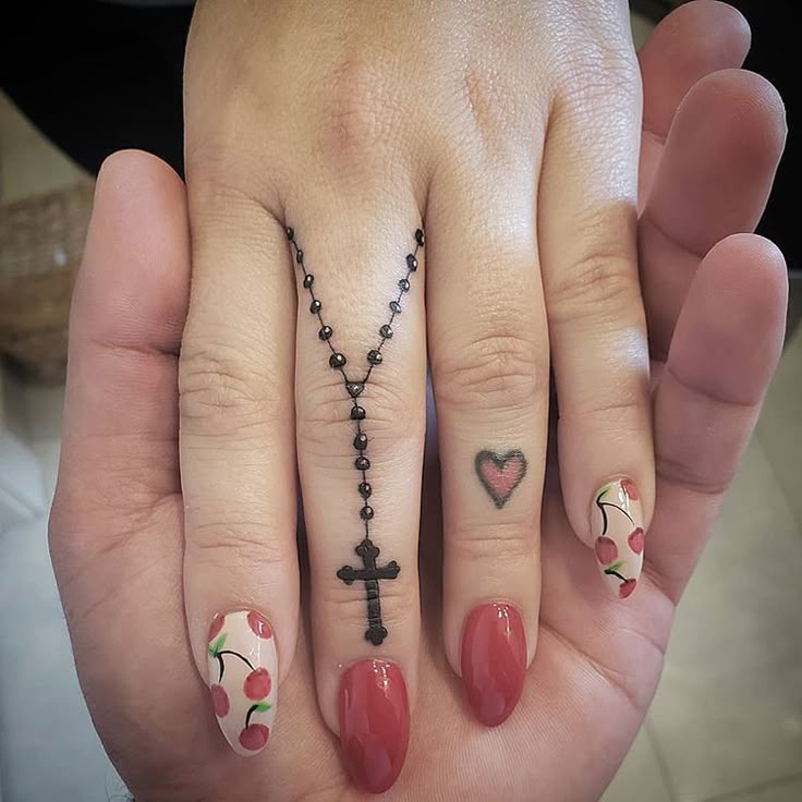 a woman's hand with a cross and heart tattoos on it