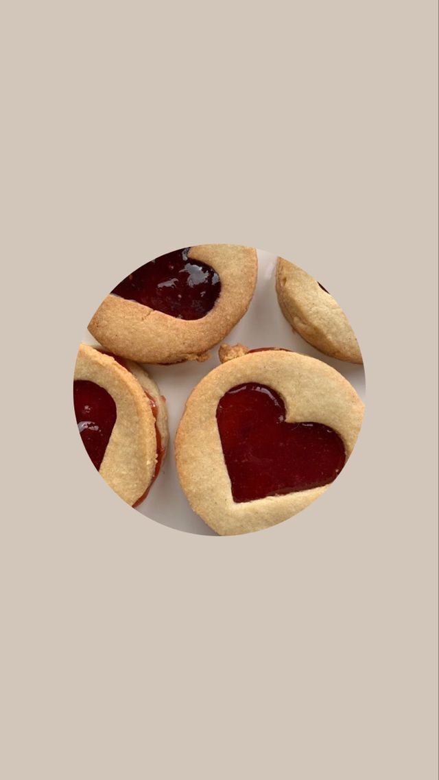 three heart shaped cookies sitting on top of a white plate next to each other with jam in the middle