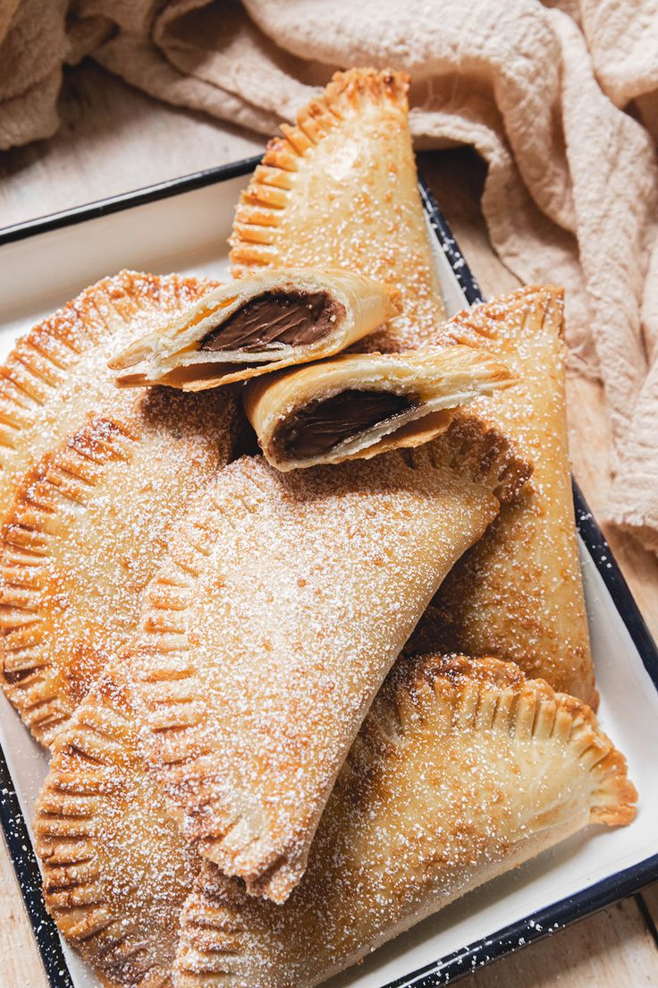 three pastries on a plate with powdered sugar