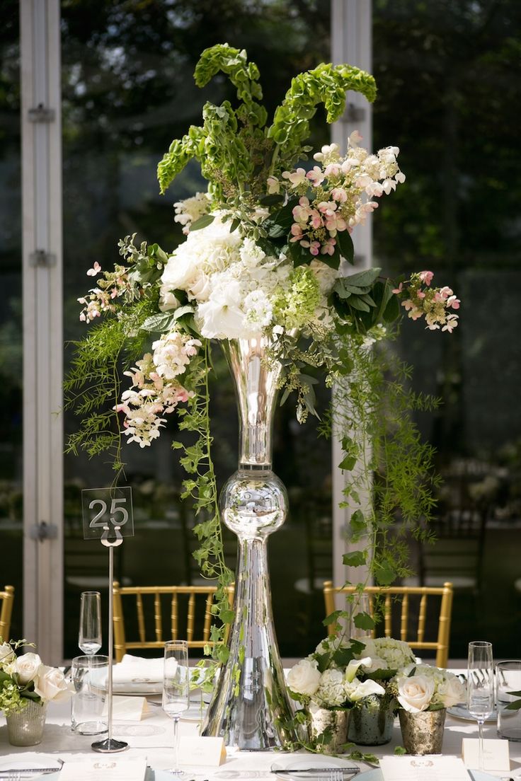 a tall glass vase filled with flowers on top of a table